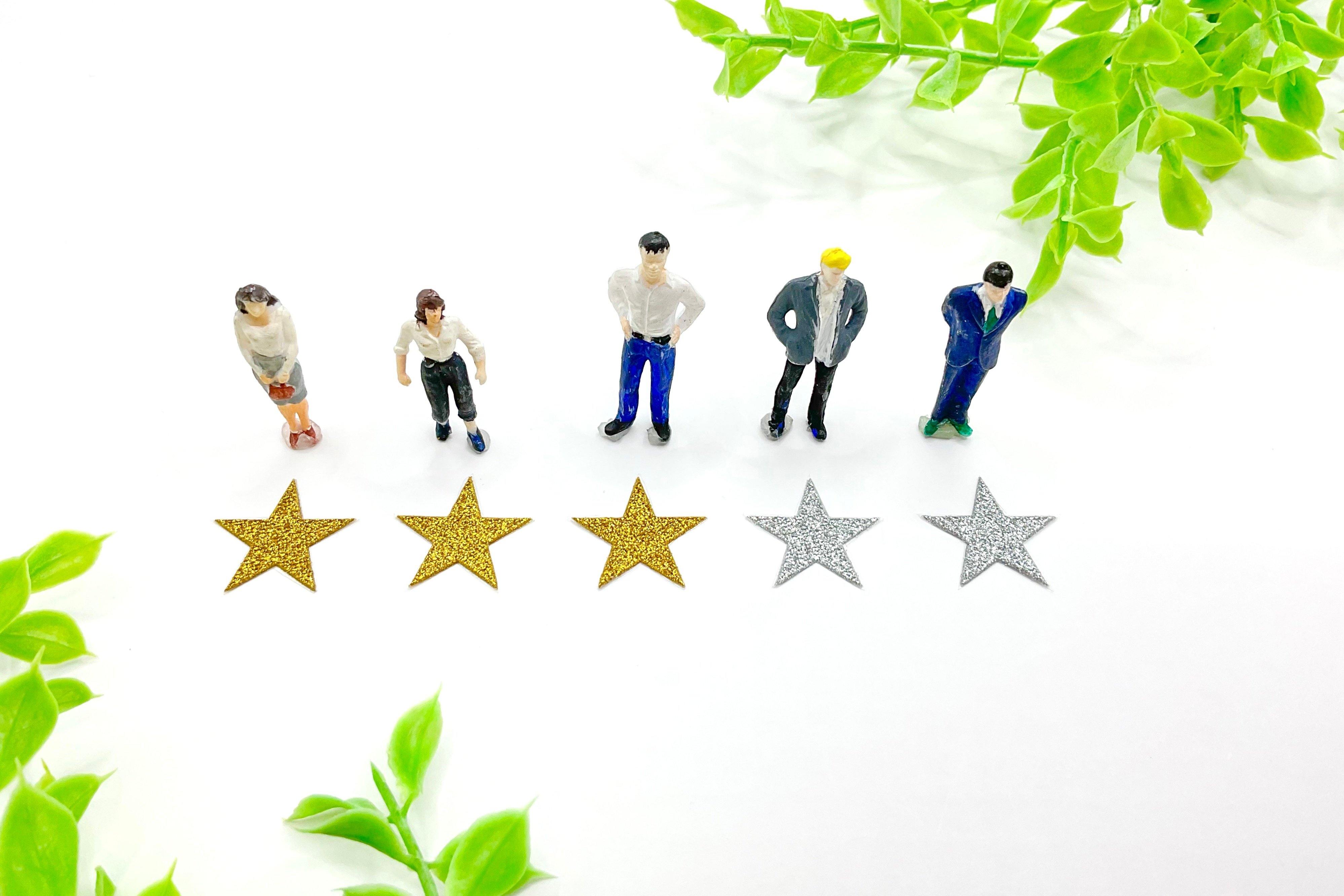 足元の星マーク評価を見つめる5人のミニチュアの人々