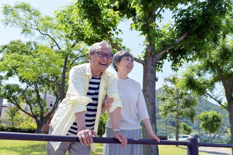 屋外で笑顔で何かを眺めるシニア男女