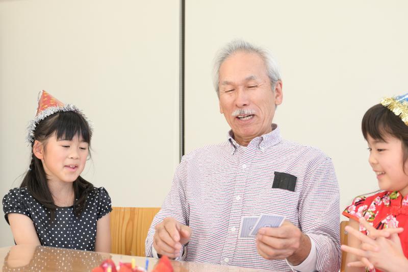 トランプで遊ぶシニア男性と女児たち