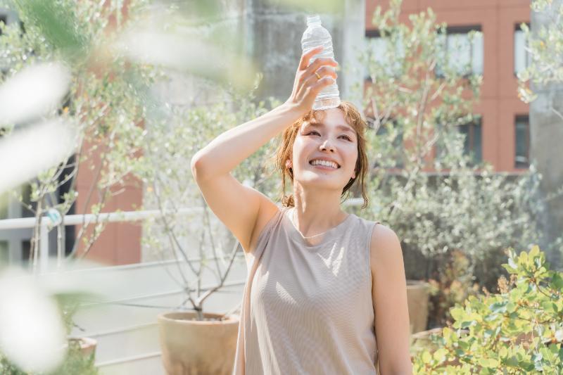 ペットボトルの水で額を冷やす女性