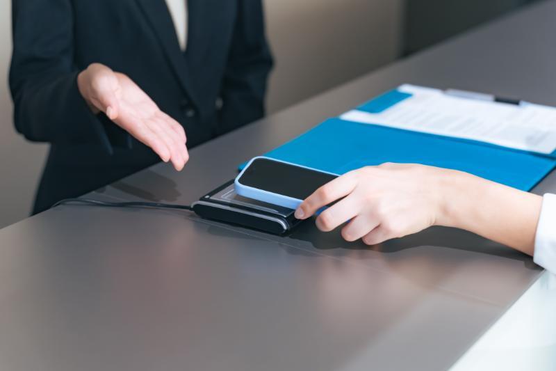 スマートフォンでタッチ決済をする人物