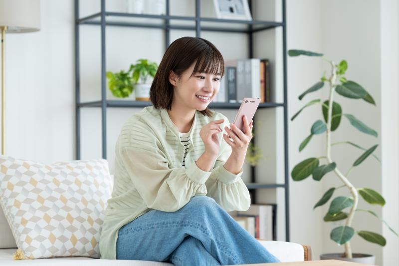 室内でスマートフォンを操作する笑顔の女性