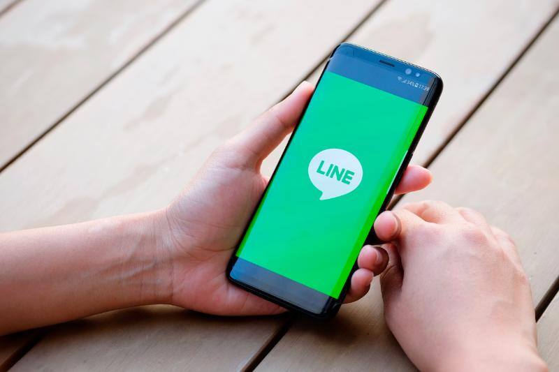 LINEを表示したスマートフォンを持つ両手